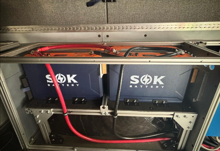 Two SOK LiFePO4 batteries installed in a custom battery compartment with heavy-gauge cabling.